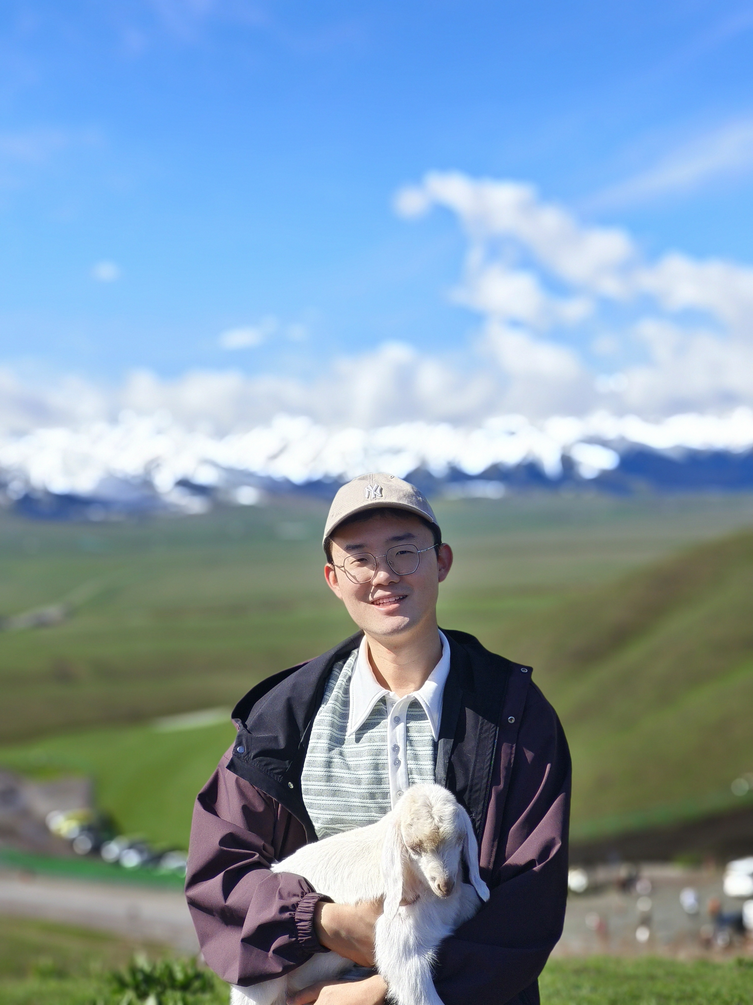 Zihao Li holding a lamb in front of snow-capped mountains